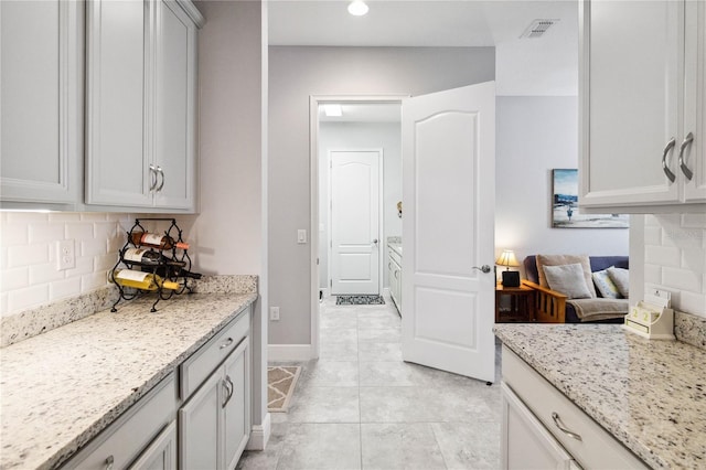 5025 Sunfalls Ave, Saint Cloud, FL 34772 - kitchen with tasteful backsplash, light stone counters, and light tile patterned floors