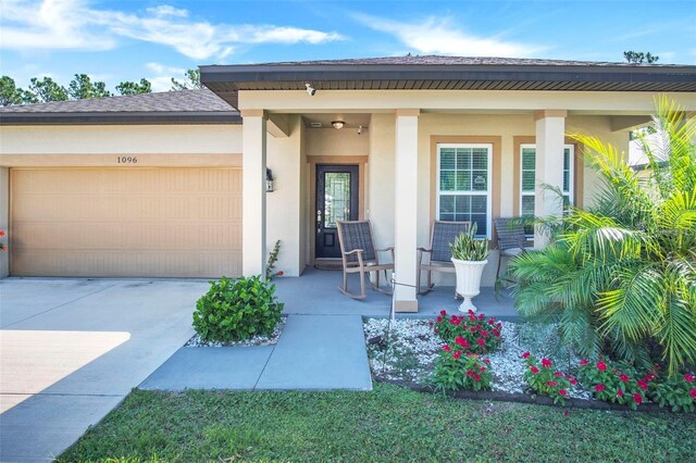1096 Roberta Rd, Lake Wales, FL 33853 - property entrance featuring covered porch, a garage, driveway, and stucco siding