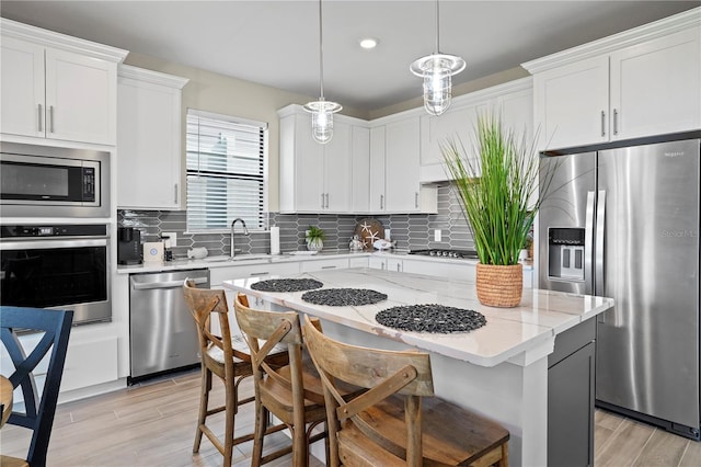 6288 Winding Pine Dr, Nokomis, FL 34275 - kitchen with appliances with stainless steel finishes, a sink, a kitchen breakfast bar, light wood-style floors, and a kitchen island