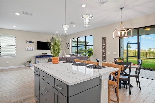 6288 Winding Pine Dr, Nokomis, FL 34275 - kitchen with gray cabinets, a kitchen island, open floor plan, light wood-type flooring, and recessed lighting