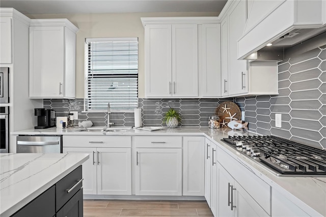 6288 Winding Pine Dr, Nokomis, FL 34275 - kitchen with stainless steel appliances, premium range hood, a sink, white cabinetry, and tasteful backsplash