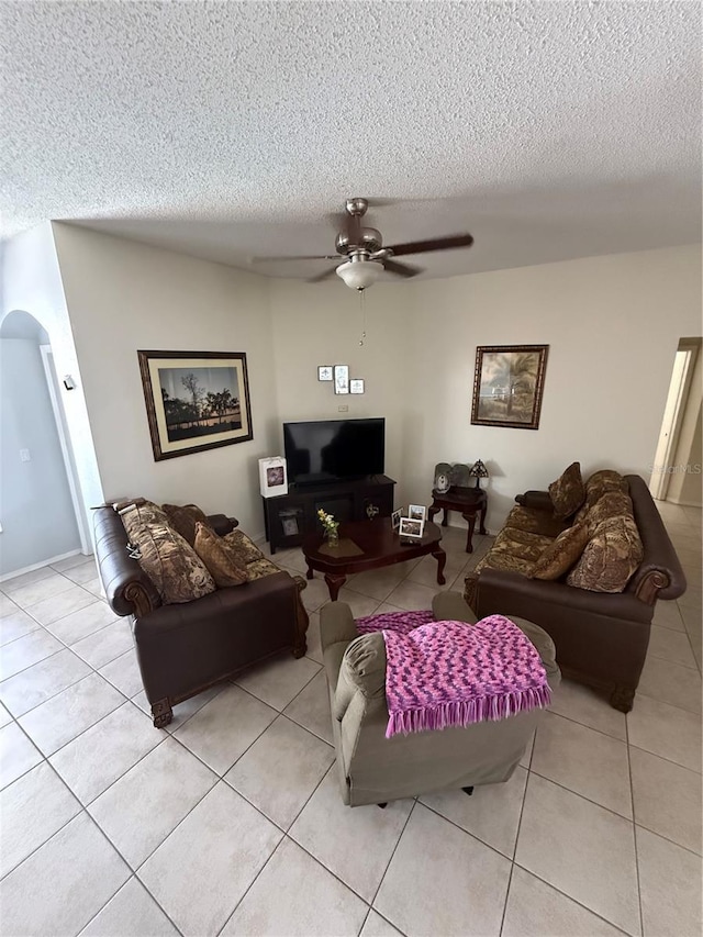 939 Jaybee Ave, Davenport, FL 33897 - living room with light tile patterned floors, a textured ceiling, a ceiling fan, and arched walkways