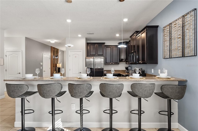 1456 Belle Terre Rd, Davenport, FL 33896 - kitchen featuring stainless steel appliances, a peninsula, dark brown cabinets, a breakfast bar, and pendant lighting