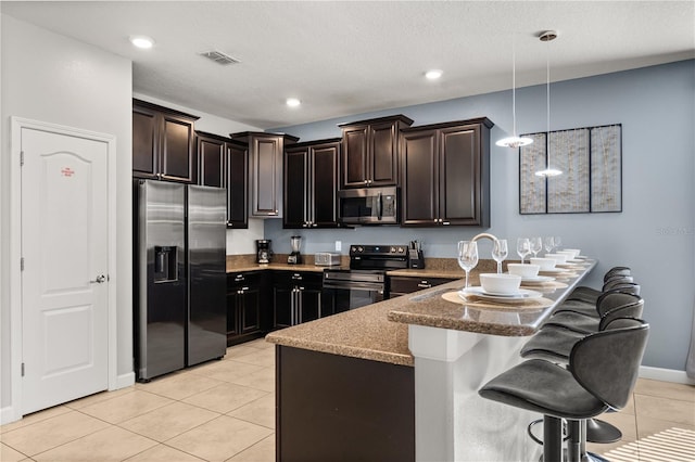 1456 Belle Terre Rd, Davenport, FL 33896 - kitchen featuring appliances with stainless steel finishes, a peninsula, light tile patterned floors, a breakfast bar, and hanging light fixtures