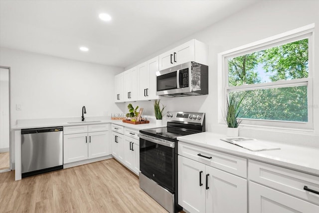 304 W 24th St, Sanford, FL 32771 - kitchen featuring stainless steel appliances, a sink, light wood-style flooring, white cabinetry, and recessed lighting