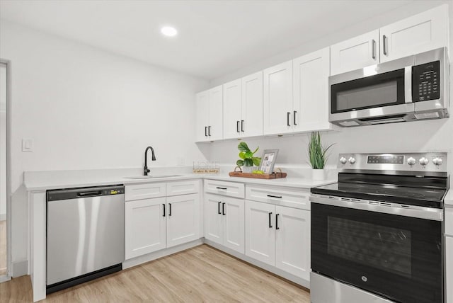 304 W 24th St, Sanford, FL 32771 - kitchen featuring stainless steel appliances, a sink, light countertops, light wood finished floors, and white cabinetry
