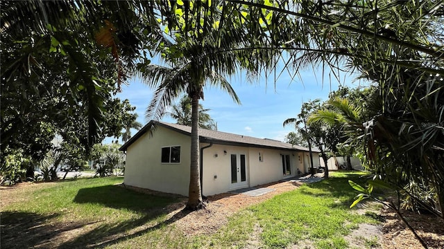 560 Gateway Dr, Merritt Island, FL 32952 - view of side of property featuring stucco siding, french doors, and a yard