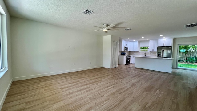 560 Gateway Dr, Merritt Island, FL 32952 - unfurnished living room featuring baseboards, light wood-type flooring, a ceiling fan, a textured ceiling, and recessed lighting