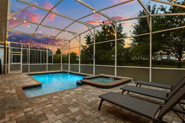 1560 Maidstone Ct, Davenport, FL 33896 - pool at dusk featuring a patio area, a pool with connected hot tub, and glass enclosure