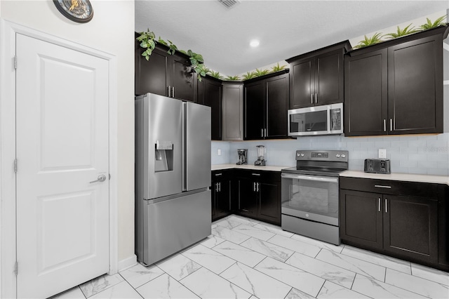 1560 Maidstone Ct, Davenport, FL 33896 - kitchen featuring stainless steel appliances, light marble finish flooring, light countertops, dark cabinetry, and recessed lighting