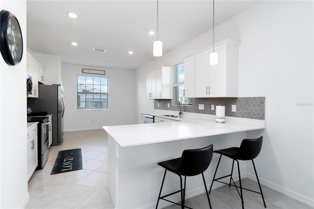 11330 Burgundy Dr, Venice, FL 34293 - kitchen featuring stainless steel appliances, light countertops, tasteful backsplash, white cabinetry, and plenty of natural light