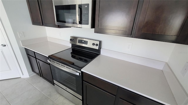 443 Cool Summer Ln, Davenport, FL 33837 - kitchen with stainless steel appliances, light countertops, light tile patterned floors, and dark brown cabinetry