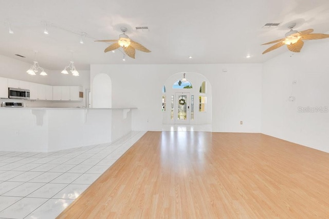 6555 Bay Tree Ct, Saint Cloud, FL 34771 - unfurnished living room with a ceiling fan, arched walkways, and light wood finished floors