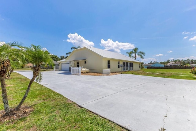 6555 Bay Tree Ct, Saint Cloud, FL 34771 - view of front of home featuring driveway, a front lawn, an attached garage, and metal roof