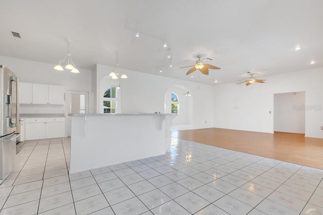 6555 Bay Tree Ct, Saint Cloud, FL 34771 - kitchen featuring stainless steel fridge, light tile patterned flooring, arched walkways, open floor plan, and a ceiling fan
