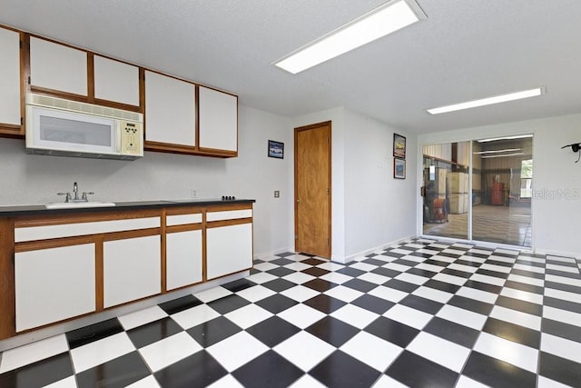 6555 Bay Tree Ct, Saint Cloud, FL 34771 - kitchen with white microwave, light floors, a sink, and white cabinetry