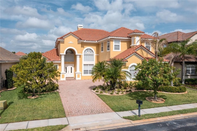 2333 Pinehurst Ct, Davenport, FL 33837 - mediterranean / spanish home with a tile roof, a chimney, decorative driveway, a front lawn, and stucco siding