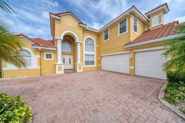 2333 Pinehurst Ct, Davenport, FL 33837 - mediterranean / spanish house with a tiled roof, decorative driveway, stucco siding, and an attached garage
