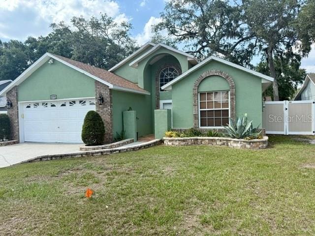 2779 Theresa Dr, Kissimmee, FL 34744 - view of front of house featuring an attached garage, concrete driveway, stucco siding, and a gate