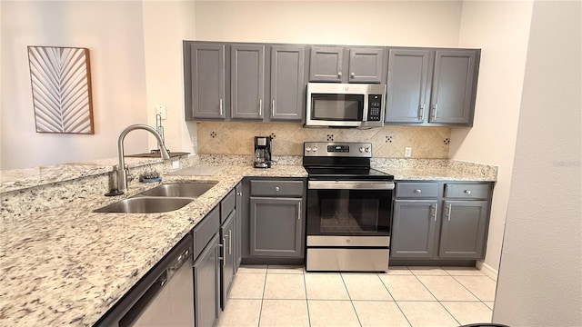 8517 Bay Lilly Loop, Kissimmee, FL 34747 - kitchen with appliances with stainless steel finishes, a sink, gray cabinets, backsplash, and light stone counters