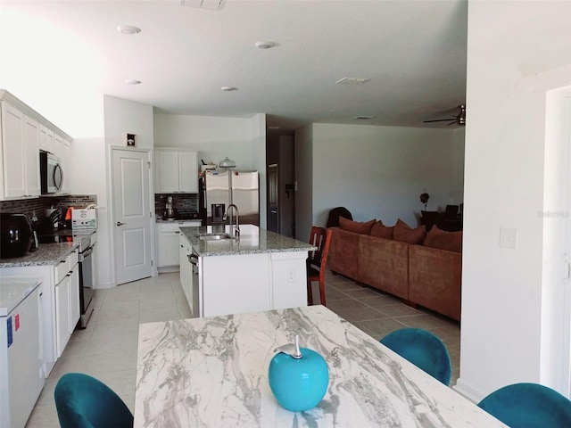 409 Conway Ave, Saint Cloud, FL 34771 - kitchen featuring appliances with stainless steel finishes, a sink, light tile patterned floors, tasteful backsplash, and white cabinetry