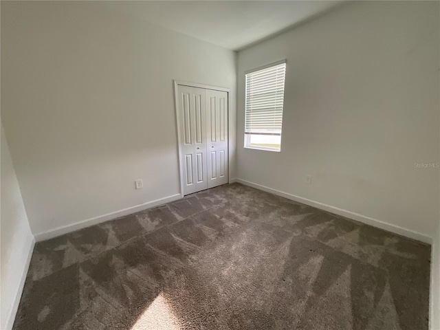 4053 Redbridge Loop, Davenport, FL 33837 - unfurnished bedroom with dark carpet, baseboards, and a closet
