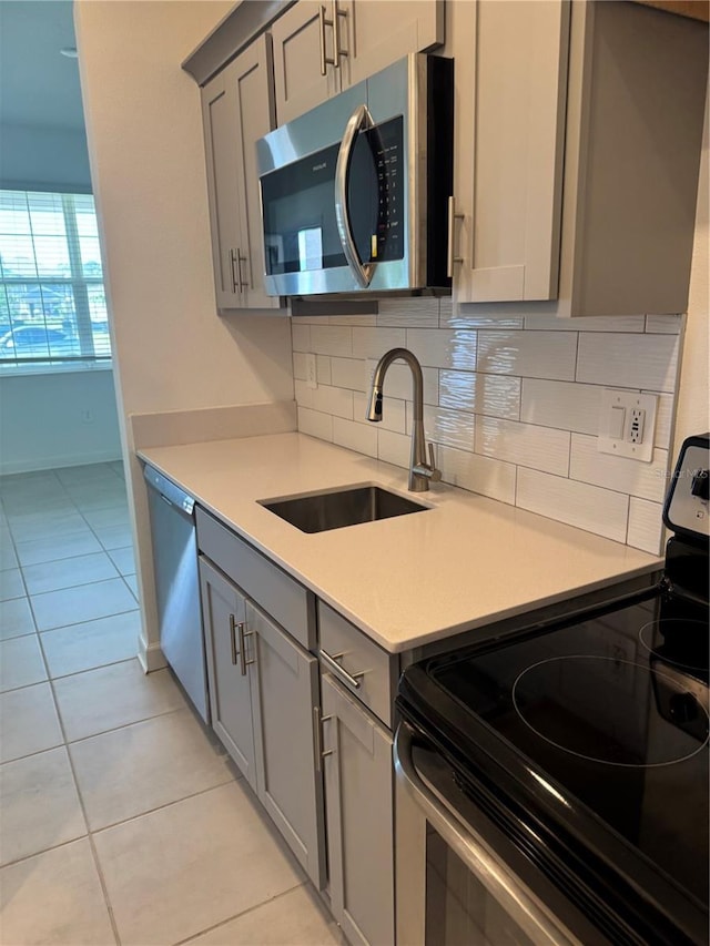 4053 Redbridge Loop, Davenport, FL 33837 - kitchen with stainless steel appliances, gray cabinetry, a sink, and decorative backsplash