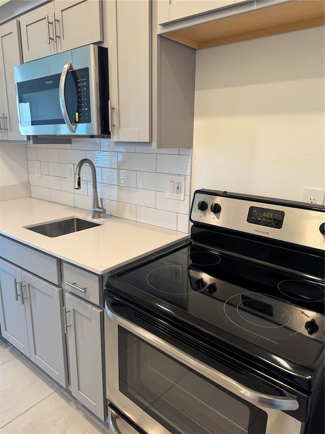 4053 Redbridge Loop, Davenport, FL 33837 - kitchen featuring appliances with stainless steel finishes, a sink, decorative backsplash, gray cabinetry, and light countertops