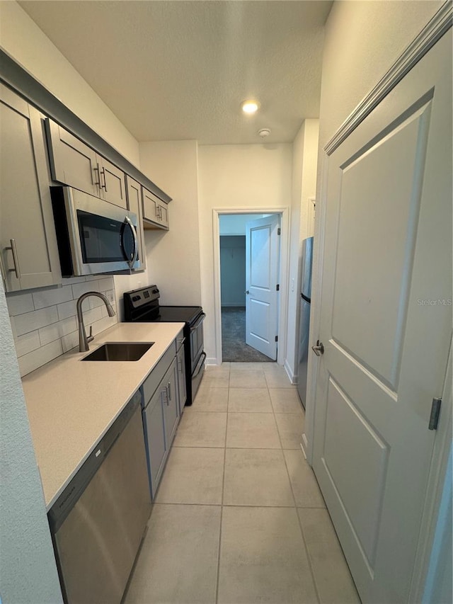 4053 Redbridge Loop, Davenport, FL 33837 - kitchen with appliances with stainless steel finishes, a sink, decorative backsplash, gray cabinets, and light countertops