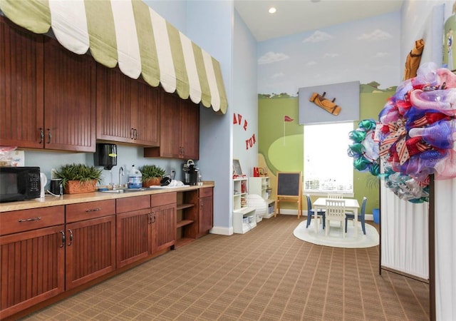 4053 Redbridge Loop, Davenport, FL 33837 - kitchen with black microwave, light carpet, light countertops, baseboards, and a sink