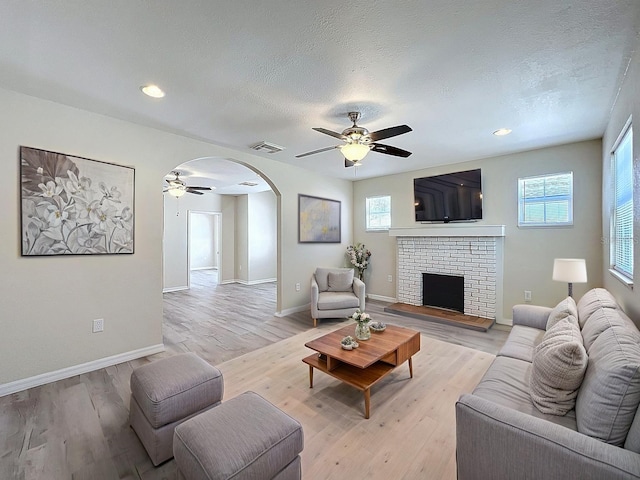 2409 E Magnolia St, Lakeland, FL 33801 - living area with ceiling fan, arched walkways, a fireplace, light wood-type flooring, and a textured ceiling