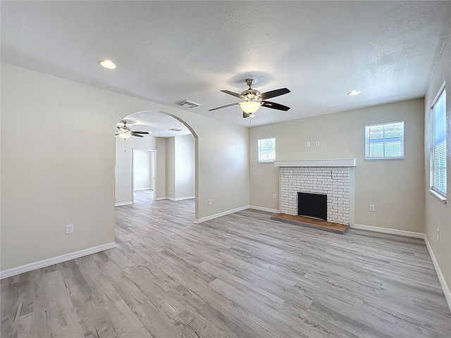 2409 E Magnolia St, Lakeland, FL 33801 - unfurnished living room with ceiling fan, light wood-style flooring, arched walkways, baseboards, and a fireplace