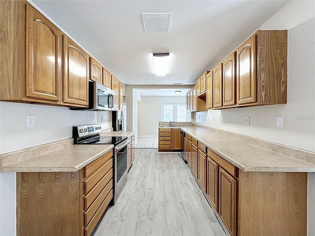 2409 E Magnolia St, Lakeland, FL 33801 - kitchen featuring appliances with stainless steel finishes, light wood-style floors, brown cabinets, and light countertops