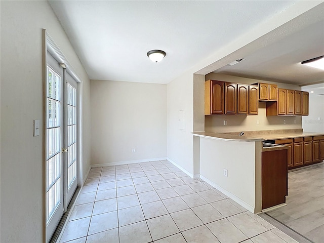 2409 E Magnolia St, Lakeland, FL 33801 - kitchen featuring a peninsula, light countertops, brown cabinetry, and baseboards
