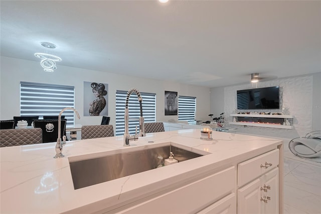 454 Hamlet Loop, Davenport, FL 33837 - kitchen featuring open floor plan, light marble finish flooring, a sink, light stone countertops, and white cabinetry