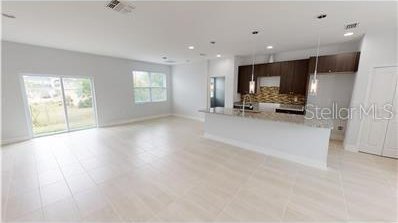 212 Grouper Ct, Poinciana, FL 34759 - kitchen with backsplash, open floor plan, light countertops, a sink, and modern cabinets