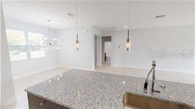212 Grouper Ct, Poinciana, FL 34759 - kitchen with light stone counters, pendant lighting, a chandelier, and baseboards