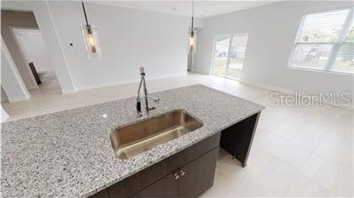 212 Grouper Ct, Poinciana, FL 34759 - kitchen with a sink, light stone countertops, and dark brown cabinetry