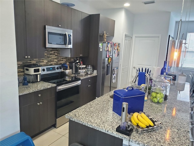 212 Grouper Ct, Poinciana, FL 34759 - kitchen with stainless steel appliances, decorative backsplash, light tile patterned floors, and light stone countertops
