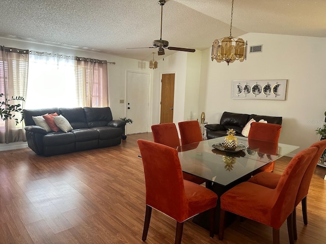 12322 Alta Mira St, North Port, FL 34287 - dining area featuring wood finished floors, a textured ceiling, a ceiling fan, a chandelier, and vaulted ceiling