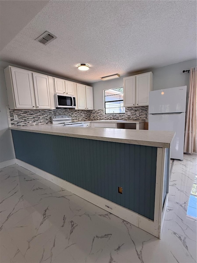 6489 Creation St, Saint Cloud, FL 34771 - kitchen featuring white appliances, white cabinets, a peninsula, decorative backsplash, and a sink