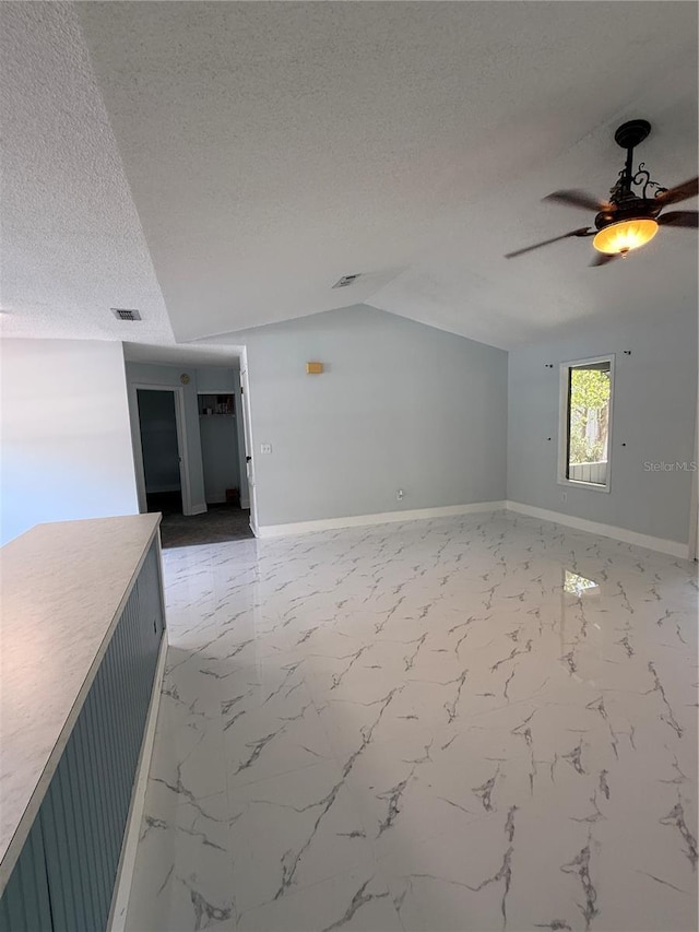 6489 Creation St, Saint Cloud, FL 34771 - empty room with ceiling fan, a textured ceiling, vaulted ceiling, baseboards, and marble finish floors