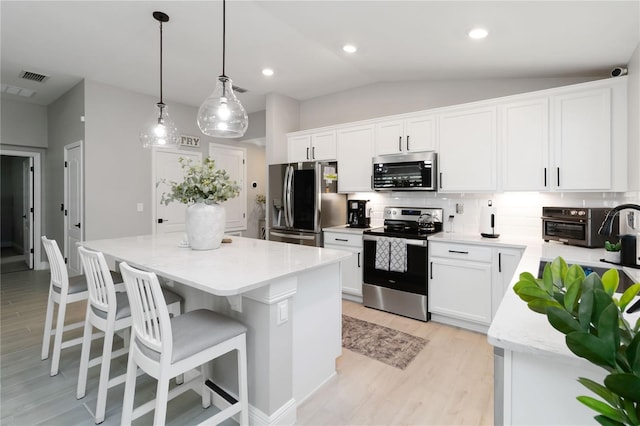 3211 Sweet Acres Pl, Saint Cloud, FL 34772 - kitchen featuring stainless steel appliances, a center island, tasteful backsplash, light wood-type flooring, and white cabinets