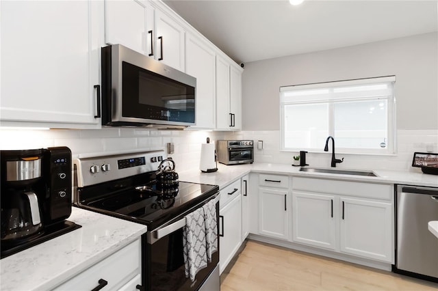3211 Sweet Acres Pl, Saint Cloud, FL 34772 - kitchen featuring appliances with stainless steel finishes, a sink, white cabinetry, decorative backsplash, and light stone counters