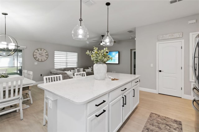 3211 Sweet Acres Pl, Saint Cloud, FL 34772 - kitchen with a kitchen island, ceiling fan, a chandelier, light wood-style flooring, and white cabinetry