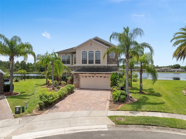 15037 Cedar Branch Way, Orlando, FL 32824 - view of front facade featuring a water view, a garage, stone siding, decorative driveway, and stucco siding