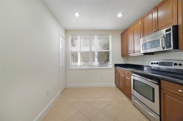 7468 Excitement Dr Unit 101, Reunion, FL 34747 - kitchen with appliances with stainless steel finishes, dark countertops, brown cabinets, recessed lighting, and baseboards