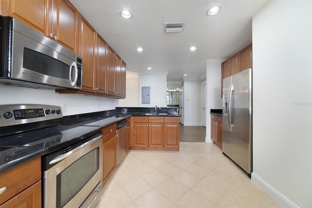 7468 Excitement Dr Unit 101, Reunion, FL 34747 - kitchen with stainless steel appliances, a peninsula, brown cabinetry, light tile patterned floors, and recessed lighting