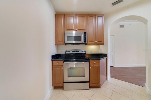 1501 Northern Harrier Way Unit 202, Reunion, FL 34747 - kitchen with appliances with stainless steel finishes, dark countertops, arched walkways, and baseboards