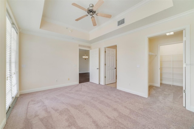 1501 Northern Harrier Way Unit 202, Reunion, FL 34747 - unfurnished bedroom featuring carpet, multiple windows, ornamental molding, a raised ceiling, and a walk in closet